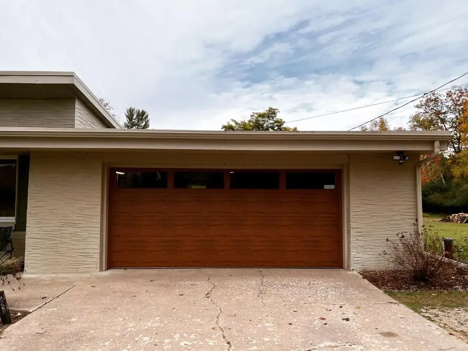 A woodgrain flush panel garage door on a mid century modern tan stucco house