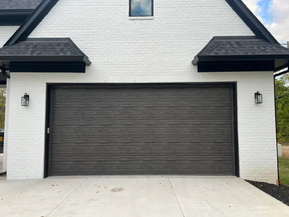 A dark woodgrain garage door on a white brick modern farmhouse
