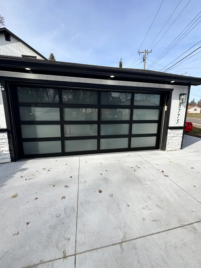A frosted full view garage door on a white brick ranch house